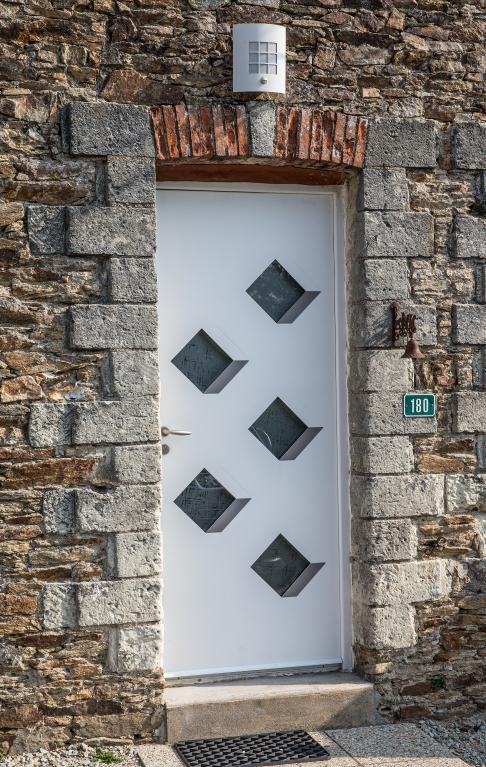 Encadrement de porte en pierres de tuffeau gris taillées spécialement pour être enduites au niveau du harpage. Cette mise en œuvre permet aux propriétaires d’acquérir des blocs de tailles différentes qui ne nécessitaient pas un travail de taille de la pierre impeccable mais qui d’apparence, après la pose de l’enduit, ont un harpage soigné. Les Perrines, Le Loroux-Bottereau. Cadastre 2018, BE 01-40. 