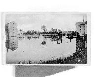 Vue d'ensemble du site depuis la rive droite en amont : façade ouest du moulin du Petit Pendu, barrage, pertuis, façade nord du moulin du Grand Pendu. En arrière-plan, le pont de chemin de fer.